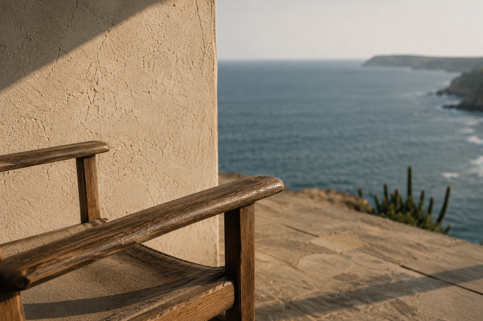 Cadeira de madeira em terraço de pedra com vista para o mar e falésias